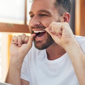 Man smiling while flossing his teeth