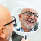 Man with black glasses smiling in reflection in mirror