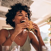 Smiling woman enjoying burger in restaurant 
