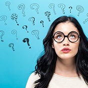 Woman looking up at several question marks