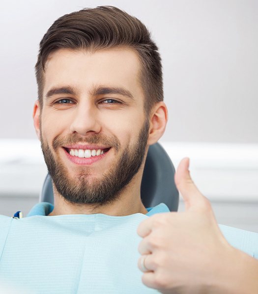 A smiling dental patient giving a thumbs up
