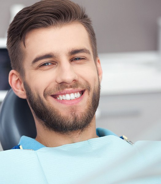 a dental patient smiling while sitting in a treatment chair