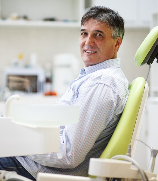 Male patient sitting in a dental chair and smiling