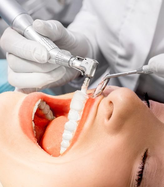A dentist performing a professional teeth cleaning on a patient