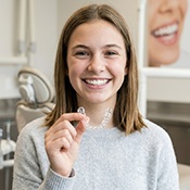 Teen girl holding clear aligner in dental office