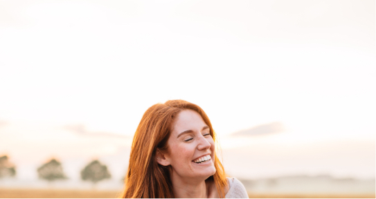Woman with red hair grinning outdoors