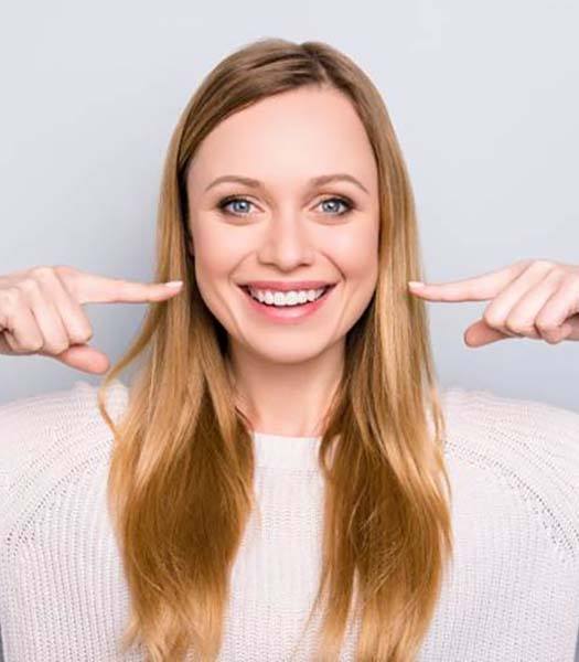 Woman pointing at her dental implants in Rancho Park