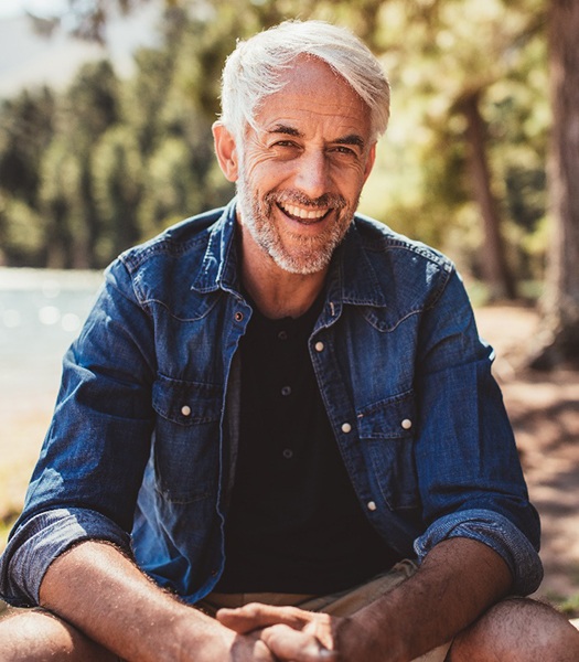 Senior man in denim jacket outside smiling