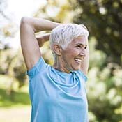 Older woman with dental implants in Rancho Park stretching outside
