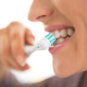 Woman with dental implants in Los Angeles, CA brushing teeth