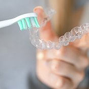 Patient using toothbrush to clean aligners