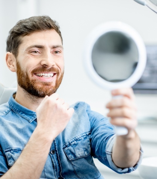 Man smiling in mirror during preventive dentistry checkup and teeth cleaning visit