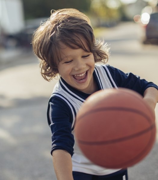 Young child playing basketball after children's dentistry visit