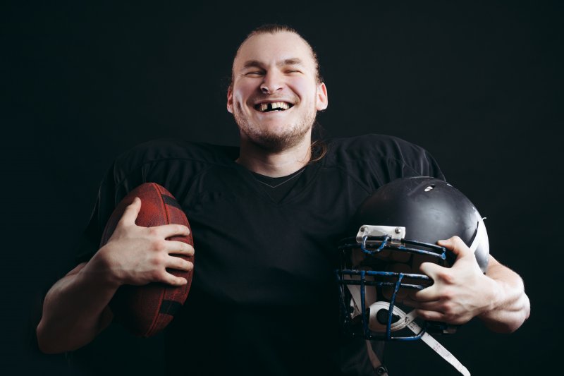 A football-playing man with a knocked-out tooth