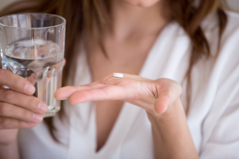 Woman holding pill and glass of water in hands