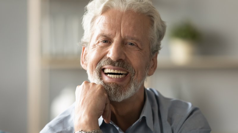An older man smiling with his partial denture replacing his missing teeth