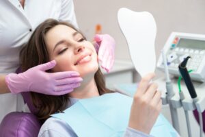 Woman looking into mirror smiling in the dentist's chair.