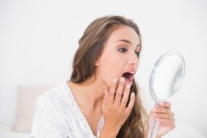 Woman looking to mirror at her shifting teeth