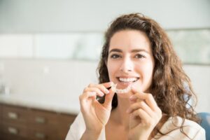 Woman holding clear aligner. 